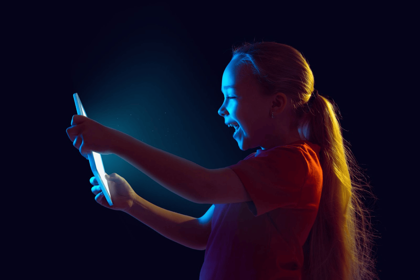 Criança segurando um tablet com luz azul refletindo no rosto