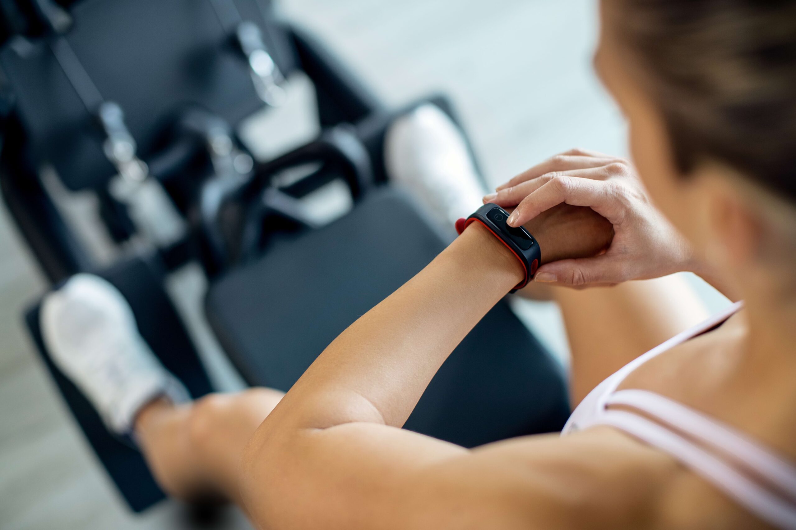 Pessoa malhando na academia em aparelho de pernas tocando no smartwatch preto no pulso