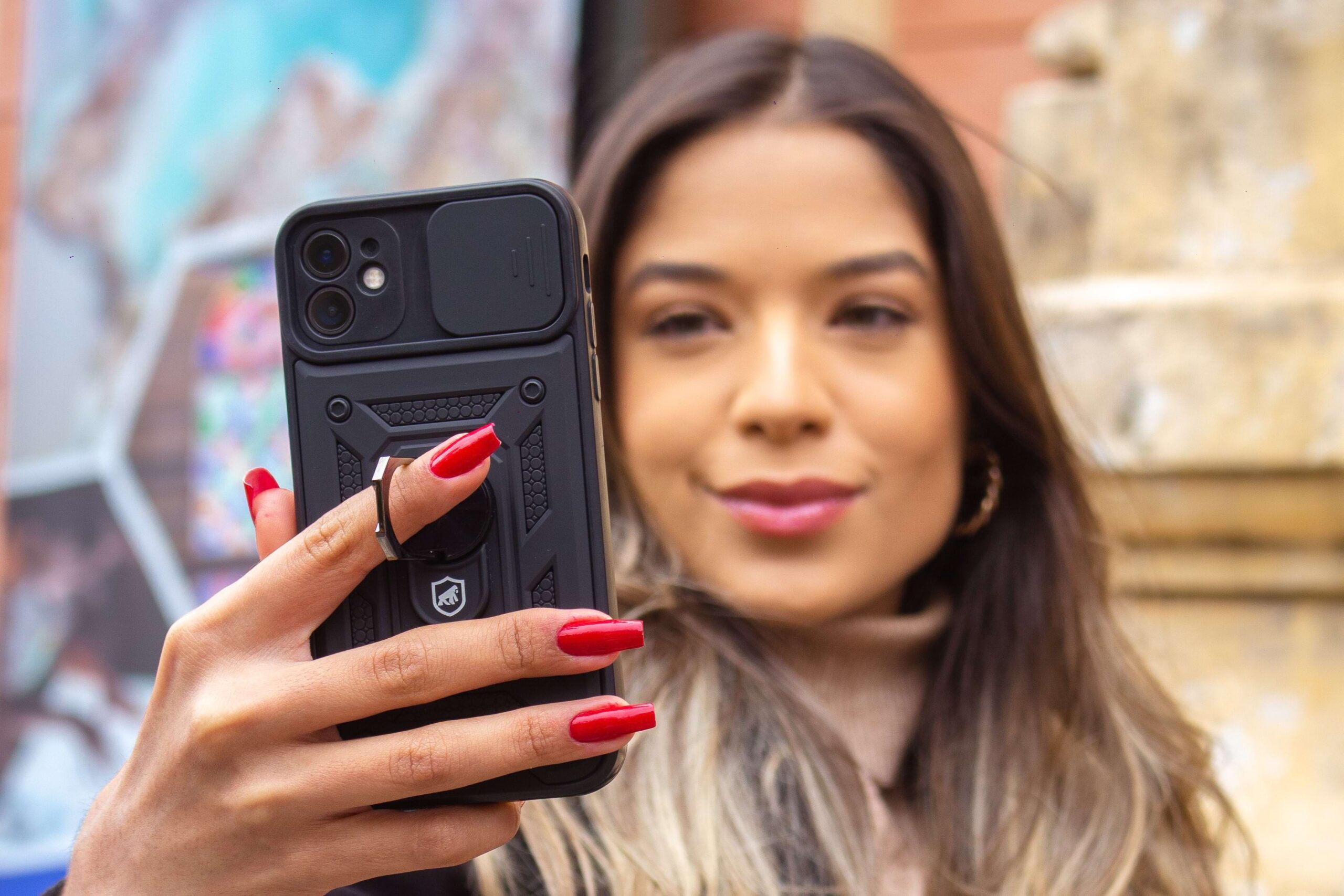 Mulher loira segurando iPhone com capa preta da GShield