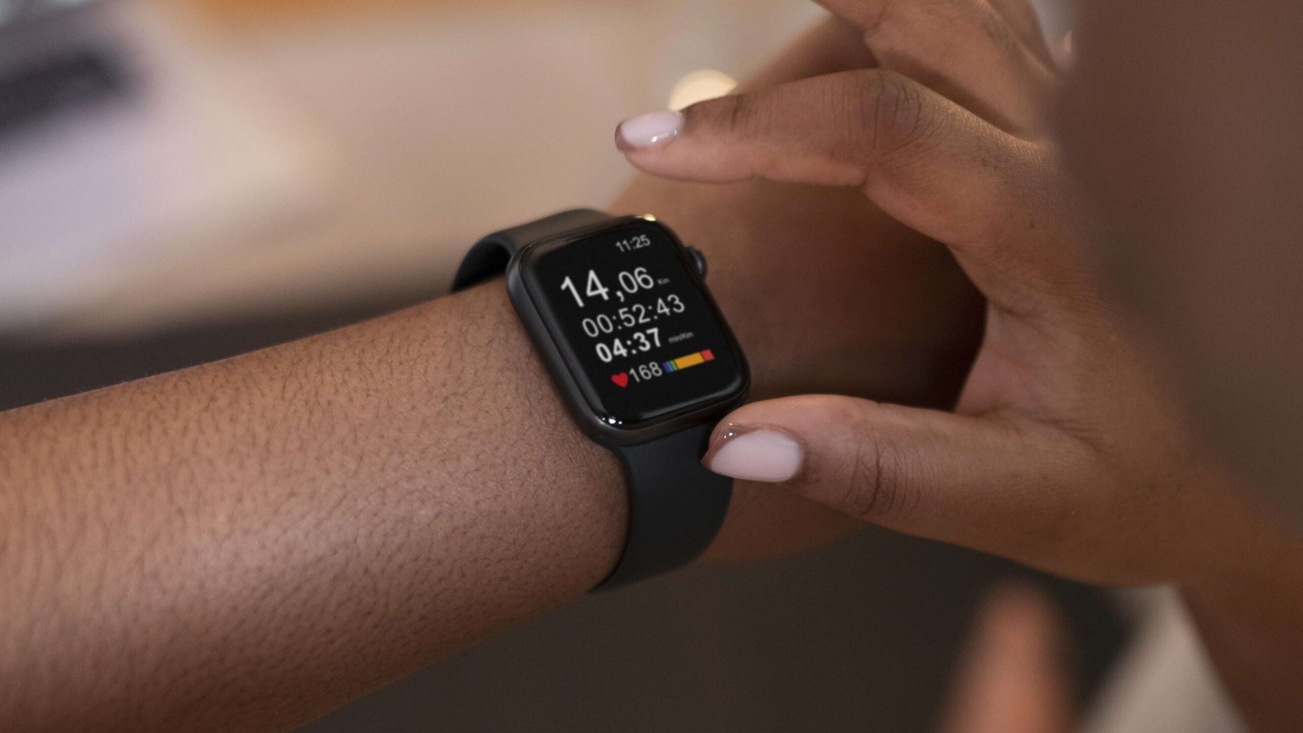 Mulher de pele negra e com unhas médias e pintadas de branco com a mão sobre o smartwatch preto