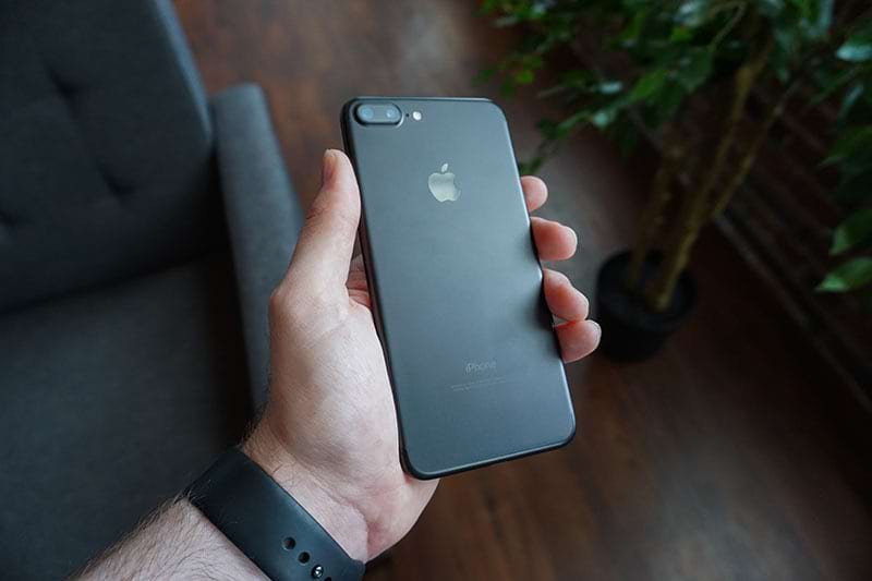 Mão masculina com relógio preto segurando um iPhone 8